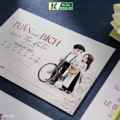 Mẫu thiệp kết hợp minh họa Chibi cô dâu chú rể cùng họa tiết hoa sen trên nền kem cổ điển, tạo cảm giác gần gũi và ấm áp. Thiết kế mang nét hoài niệm nhưng vẫn hài hòa với phong cách cưới hiện đại.