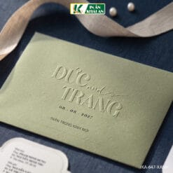 Mẫu thiệp cưới nổi bật với gam xanh olive nhẹ kết hợp nền trắng, tạo tổng thể thanh lịch và hiện đại. Điểm nhấn chính nằm ở phần tên trên bìa được dập nổi cùng lót thiệp cắt hình hoa.