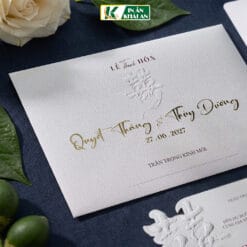 Mẫu thiệp cưới sử dụng nền kem trắng làm chủ đạo, kết hợp chữ nâu và chi tiết ép kim vàng nhẹ. Thiết kế hiện đại pha nét Asian Luxury, nổi bật với họa tiết chữ Hỷ dập nổi.